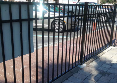 A black wrought iron fence with a car parked next to it.