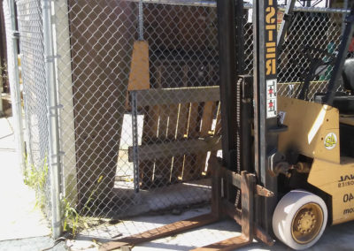 A forklift is parked in front of a fence.