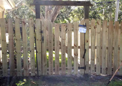 A wooden fence in a backyard with a gate.