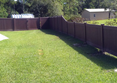 A backyard with a brown fence and grass.