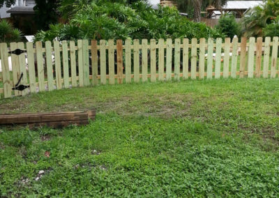 A wooden picket fence in a yard.