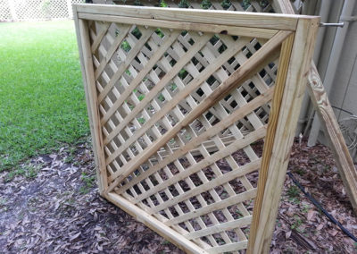 A wooden lattice fence in a backyard.